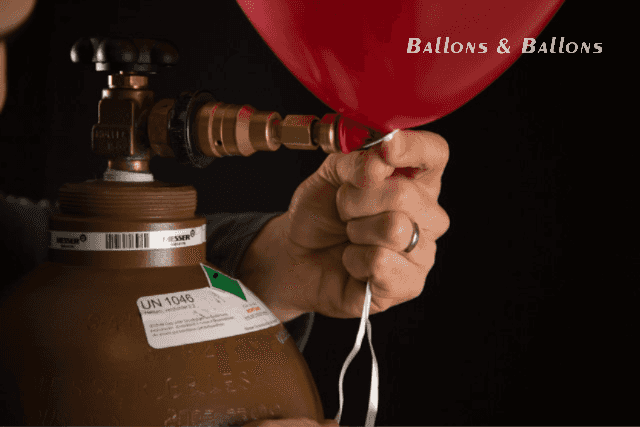 Eine Hand hält einen roten Ballon an eine Propanflasche in Wien.