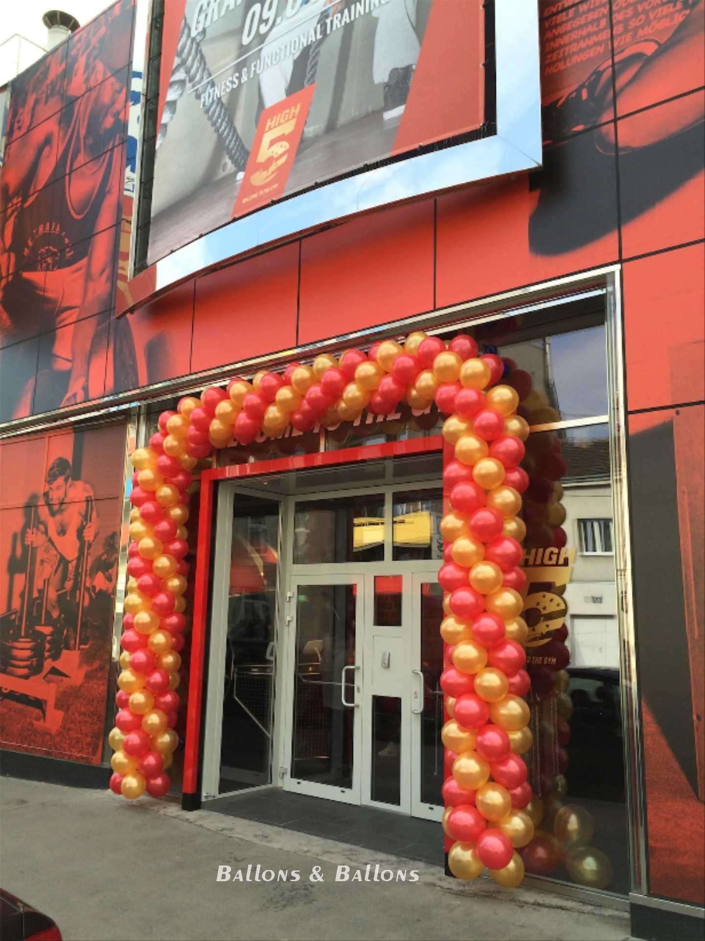 Ein leeres rotes und goldenes Gebäude mit einem großen orangefarbenen Ballonbogen in Wien