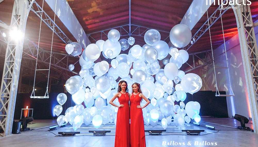 Zwei Frauen in roten Kleidern neben einer Wand aus Ballons in Wien.
