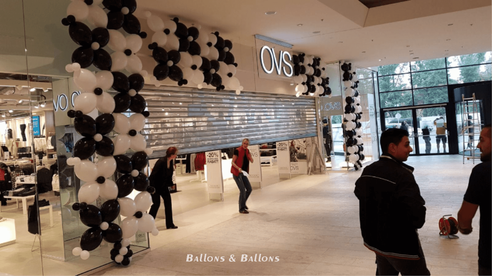 Eine Gruppe von Menschen steht vor einem Geschäft mit Schwarz- und Weißballons in Wien.