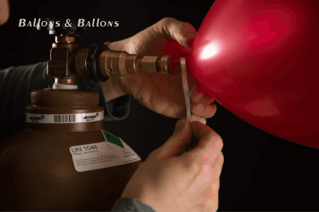 Ein Mann befestigt ein Gummiband an einem Heliumballon in Wien.