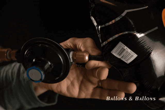 Jemand verwendet einen Schlauch, um einen schwarzen Ballon aufzublasen in Wien.